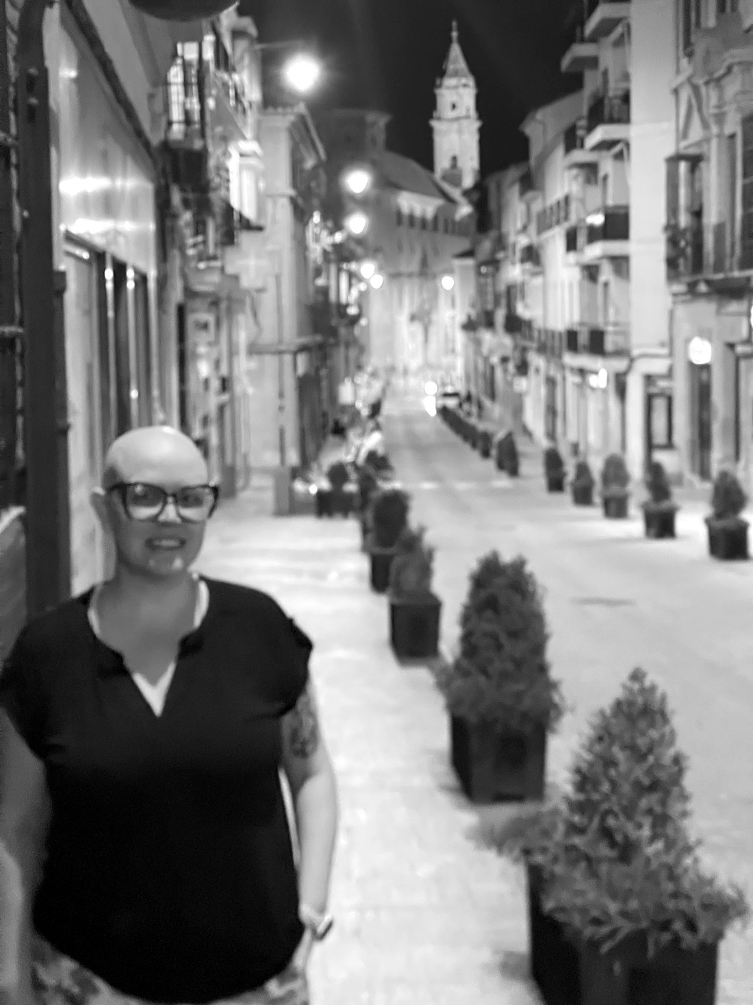 Laura Cole smiling on a lamplit street in Spain at night, a church tower behind her