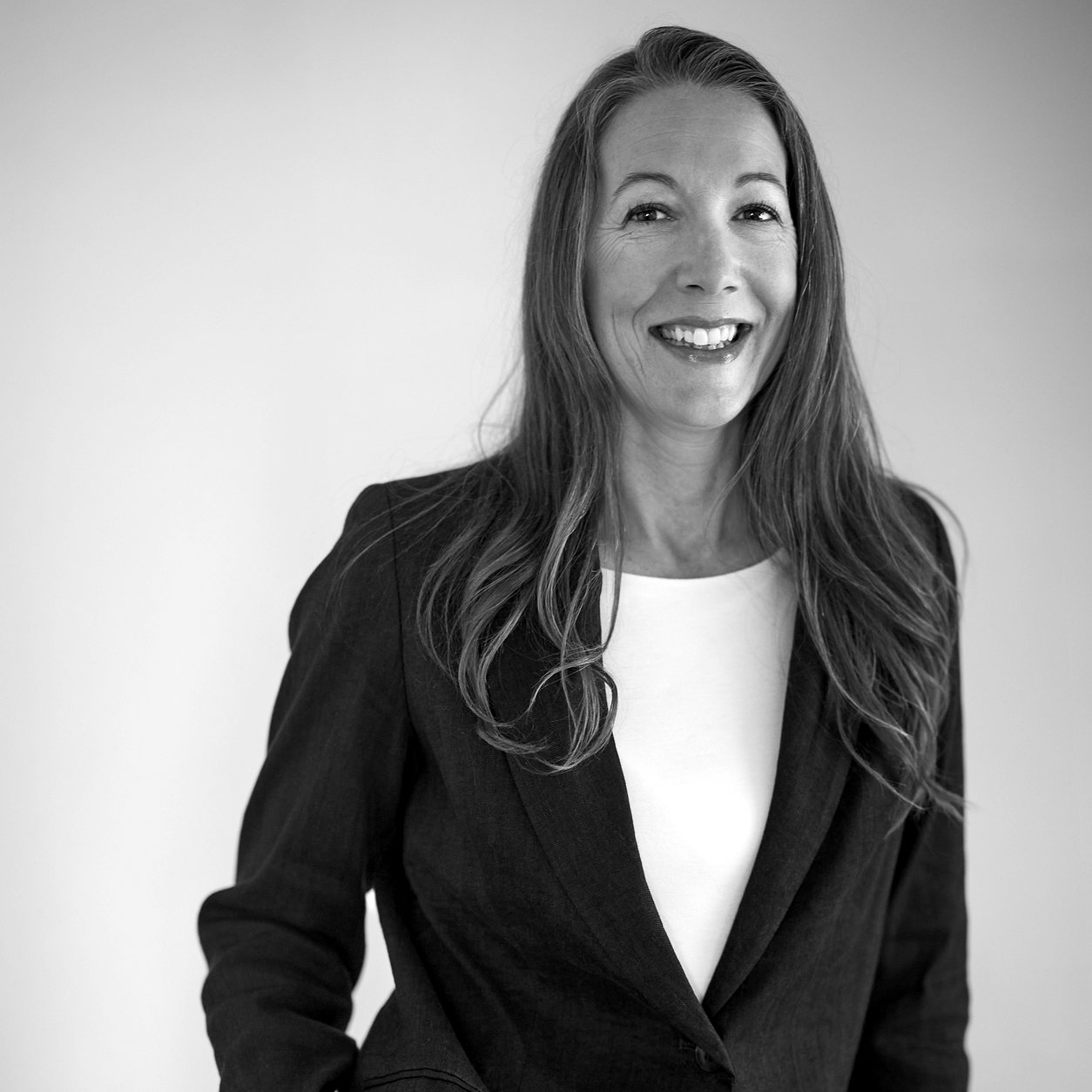 Monica Phillips smiling, in a dark blazer over a white top