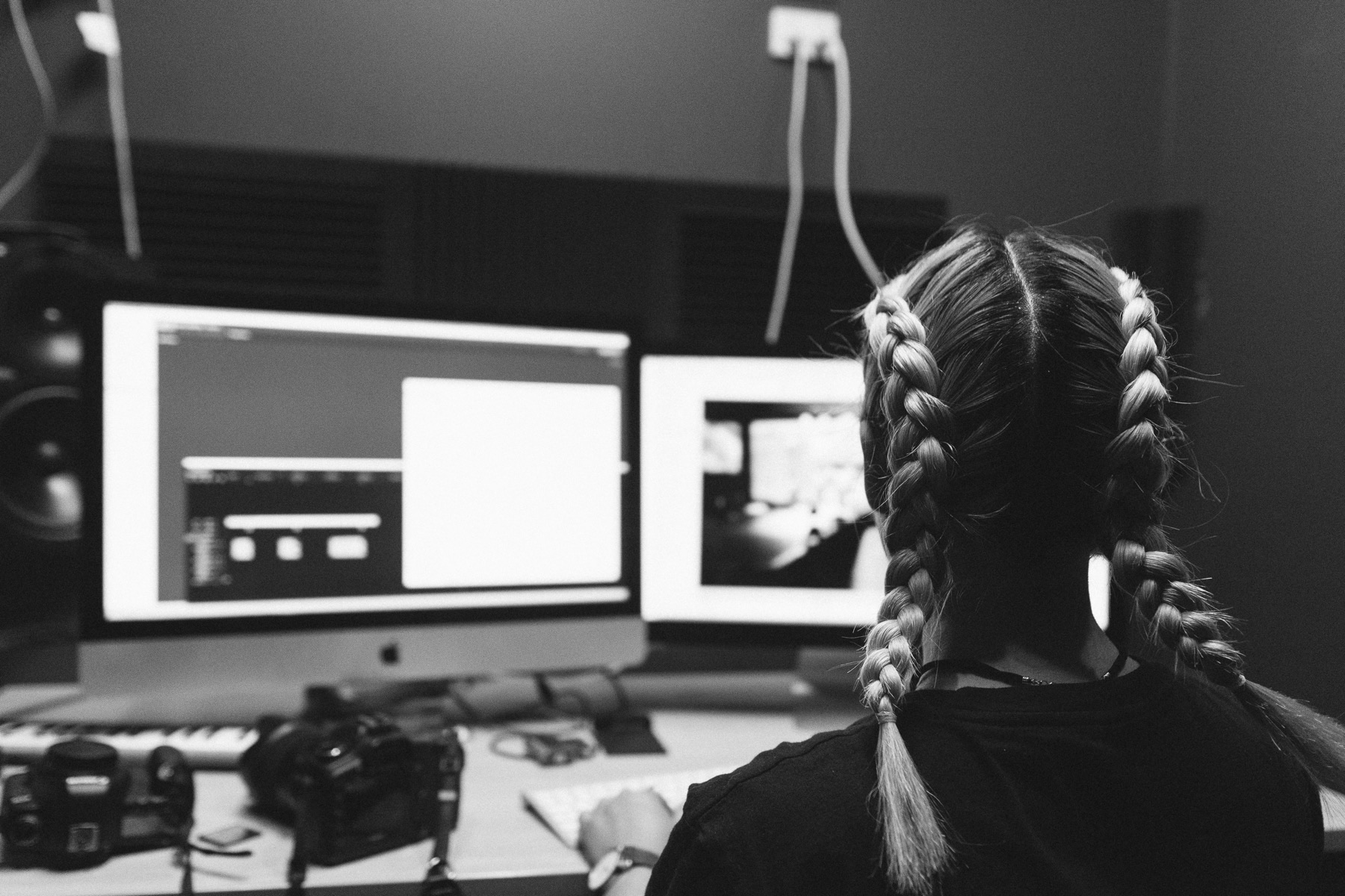 A woman working at a desk in front of two computer monitors